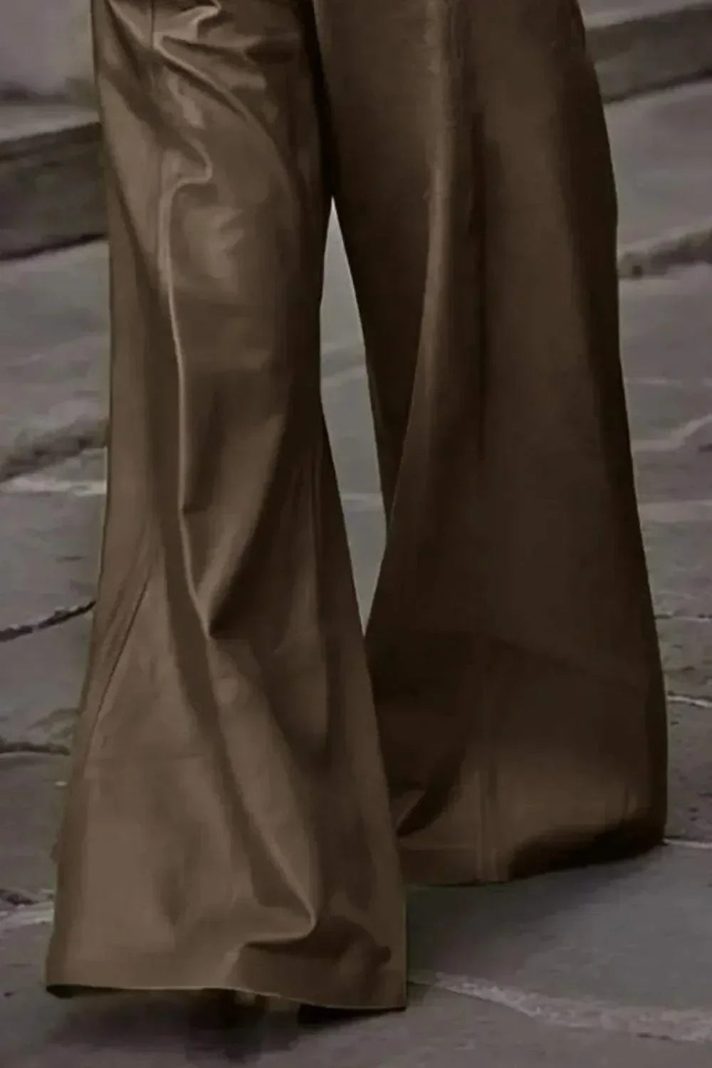 Close-up of wide-leg brown leather pants on stone pavement