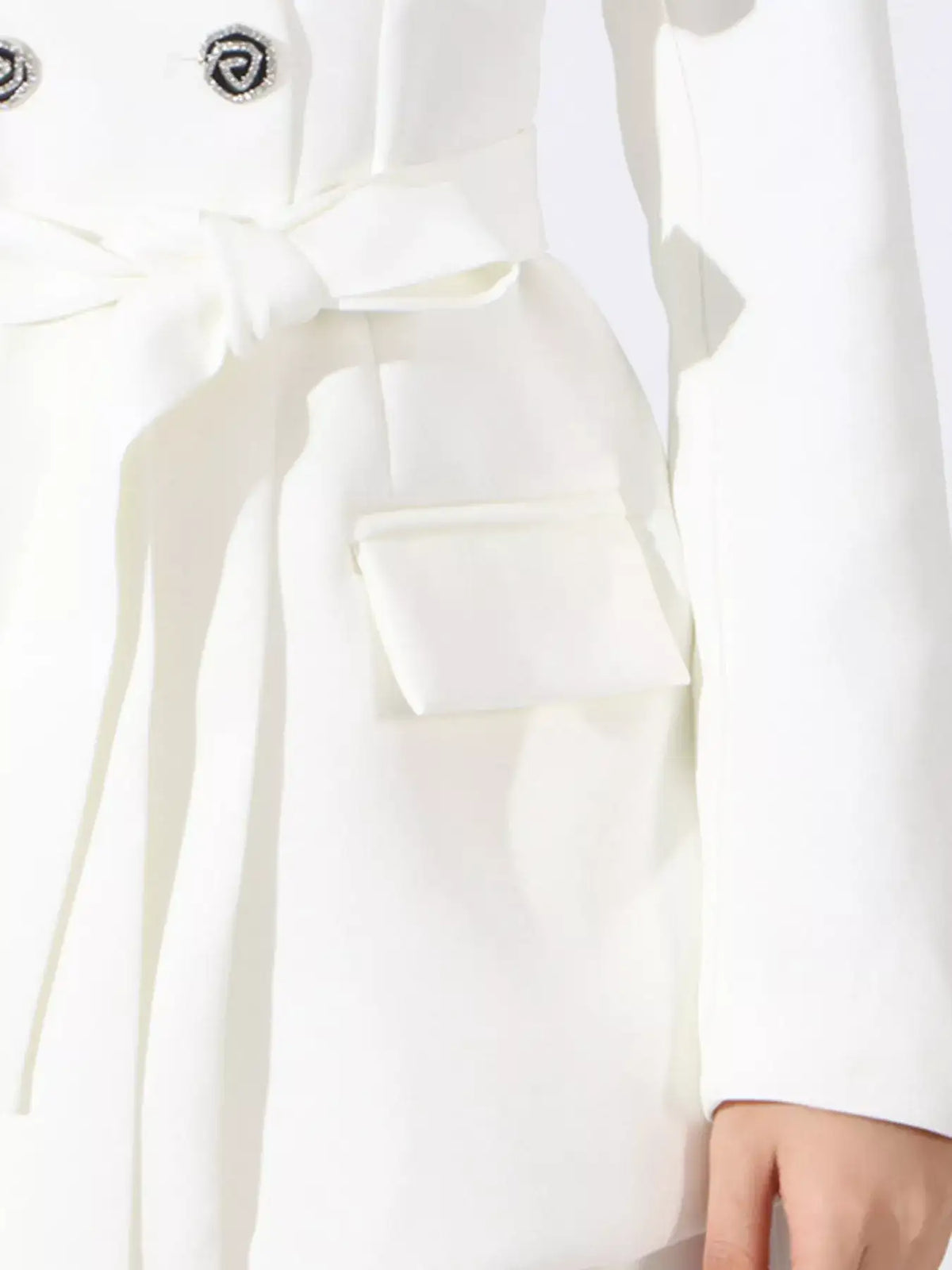 Close-up of a white Evie's Dreamland double-breasted blazer featuring a tie-waist and decorative buttons.