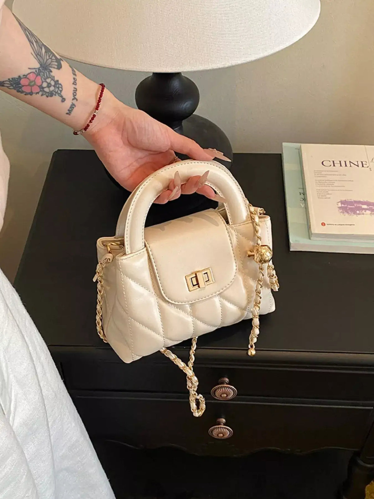 Evie's Dreamland cream quilted PU leather crossbody bag with gold chain strap and top handle.