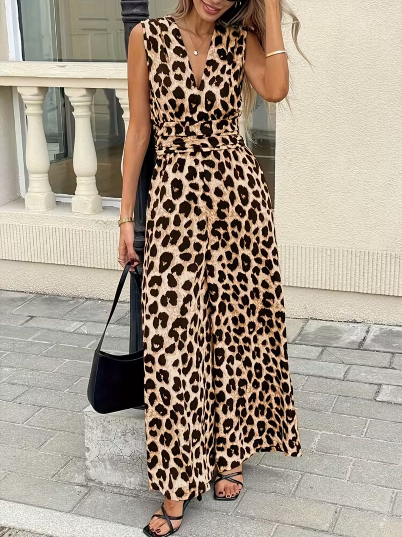 Woman wearing a sleeveless leopard print jumpsuit with wide legs and black sandals