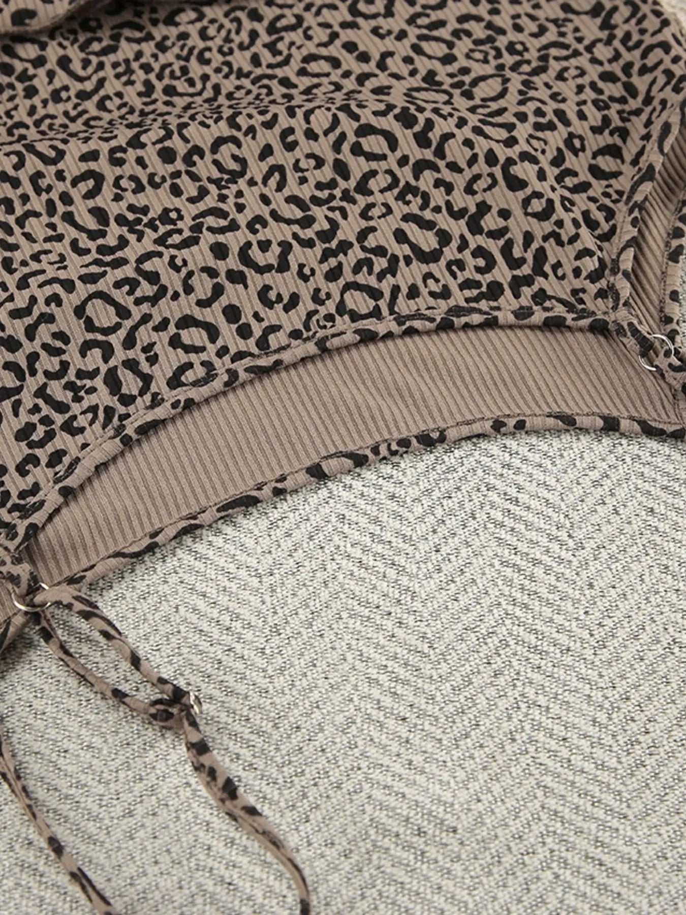 Close-up of brown leopard print fabric with ribbed texture and drawstring detail on gray textured surface