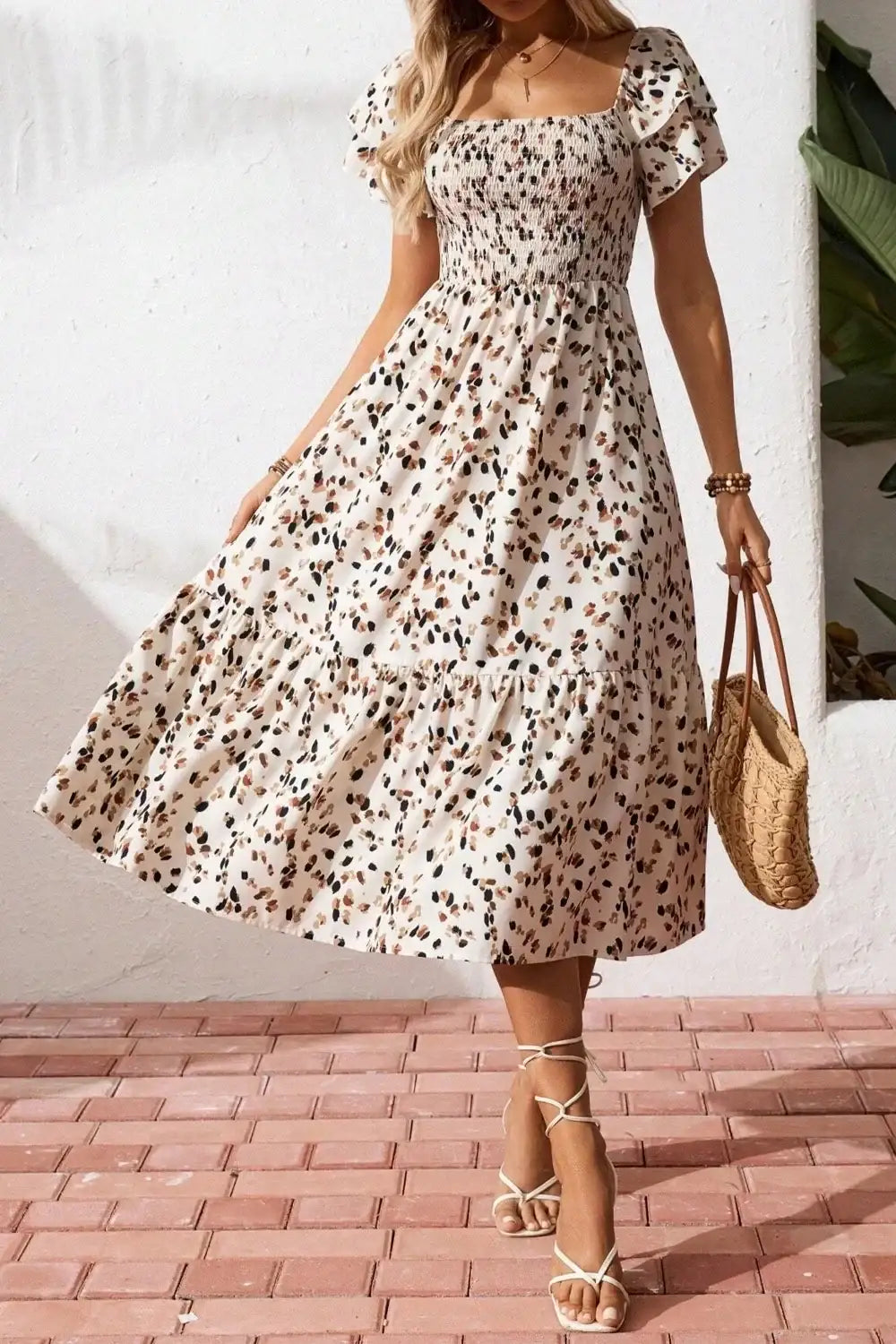 Floral midi dress with puff sleeves, tiered skirt, and square neckline, paired with straw bag and sandals