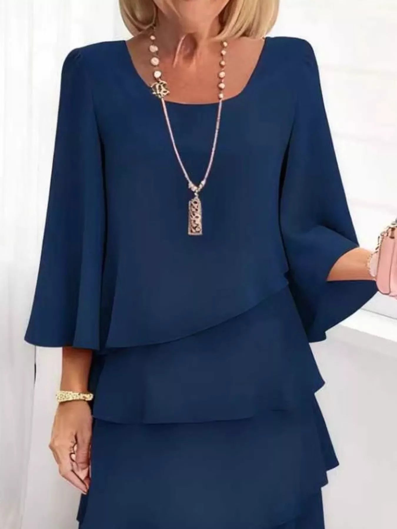 Navy blue ruffled dress with bell sleeves, paired with elegant necklace and bracelet for chic everyday style.