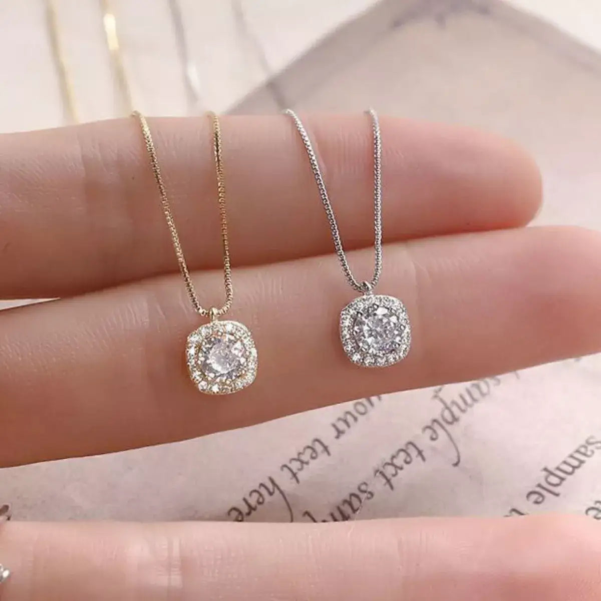 Gold and silver Evie's Dreamland 925 sterling silver zircon pendant necklaces held in a hand.