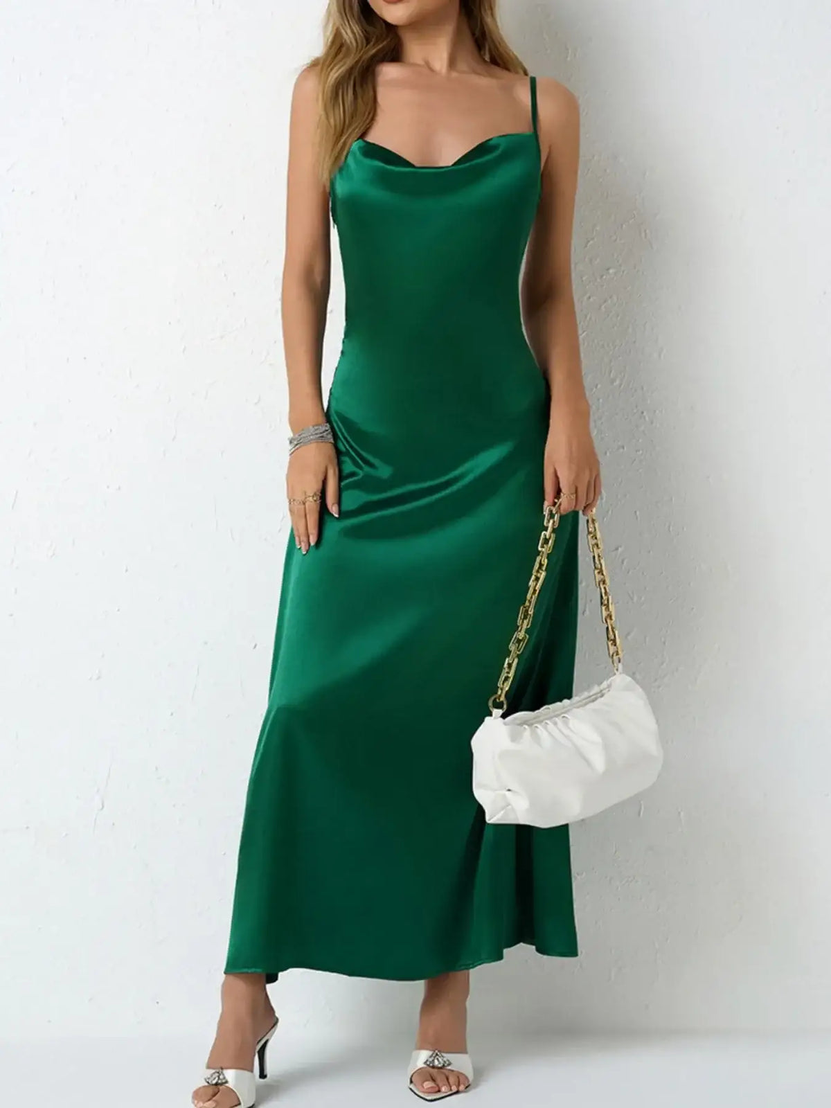 Woman wearing an Evie's Dreamland green satin cowl neck slip maxi dress with a white handbag.