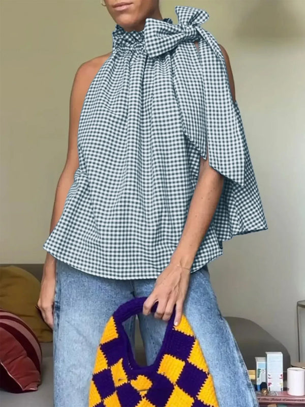 Woman wearing a gingham bow top, blue jeans, and holding a yellow purple knit tote bag.