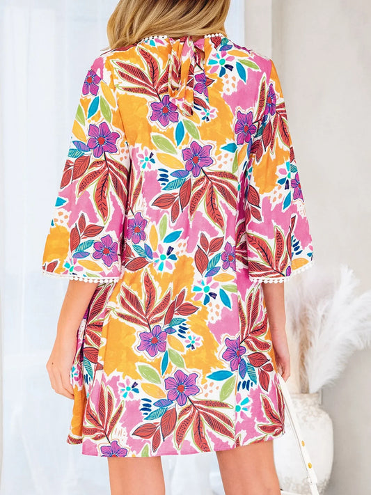 Woman wearing colorful floral print dress with bell sleeves and tie-back detail