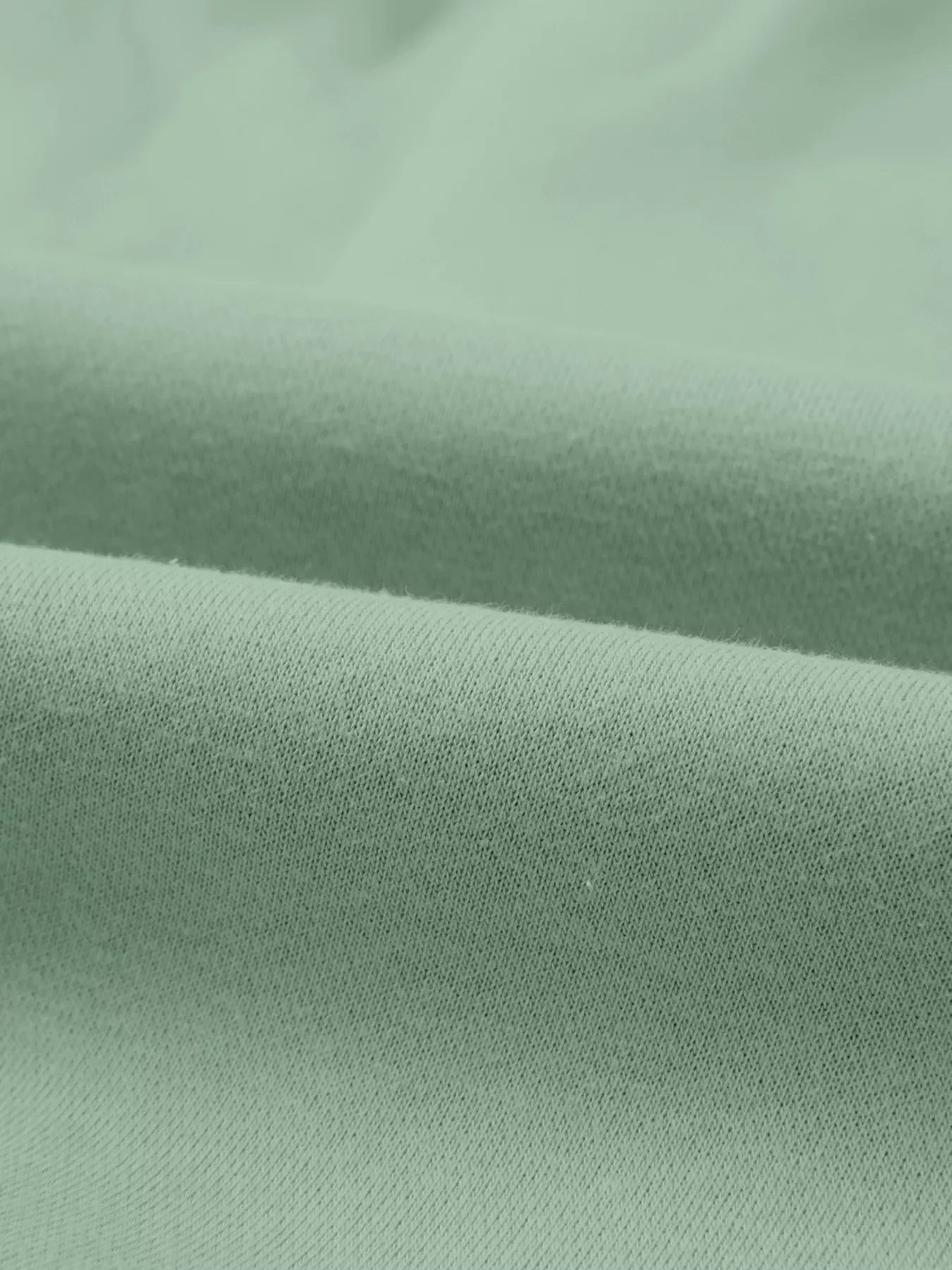 Smooth mint green fabric textile close-up with soft folds and fine texture