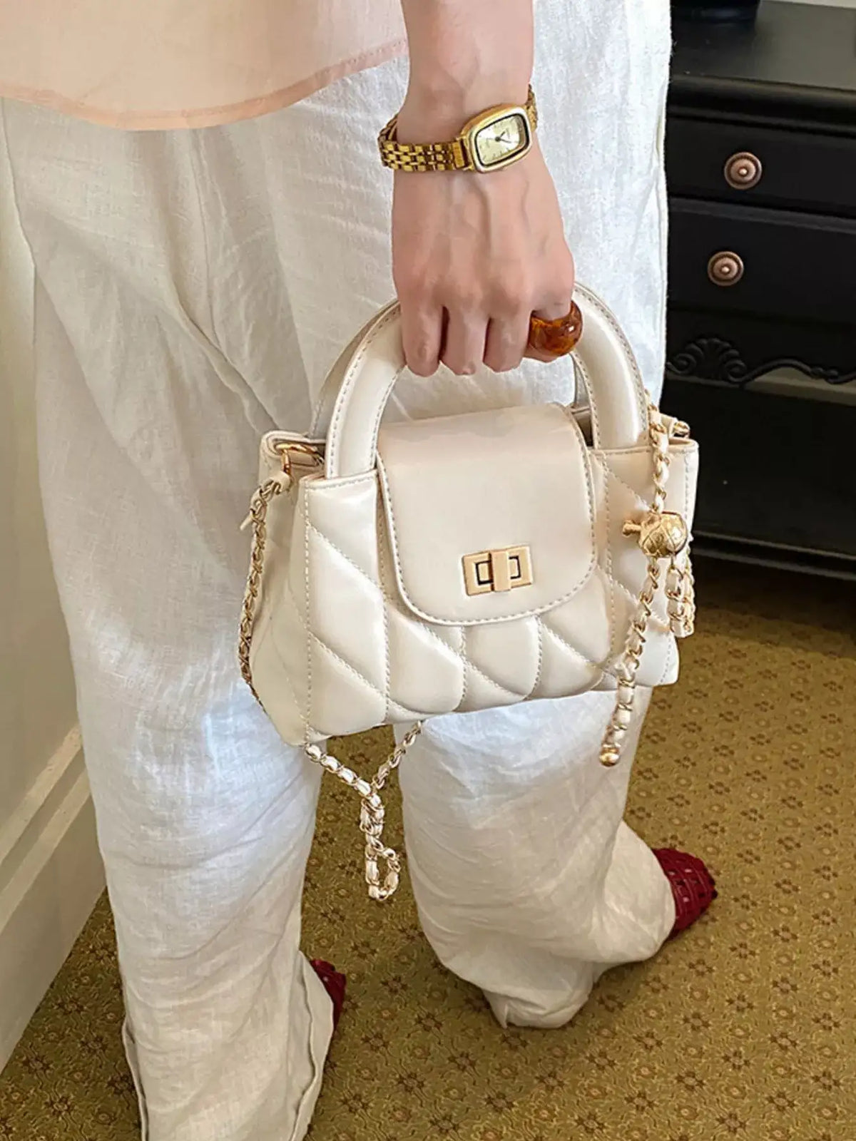 Evie's Dreamland cream quilted PU leather crossbody bag with gold chain strap and top handle.