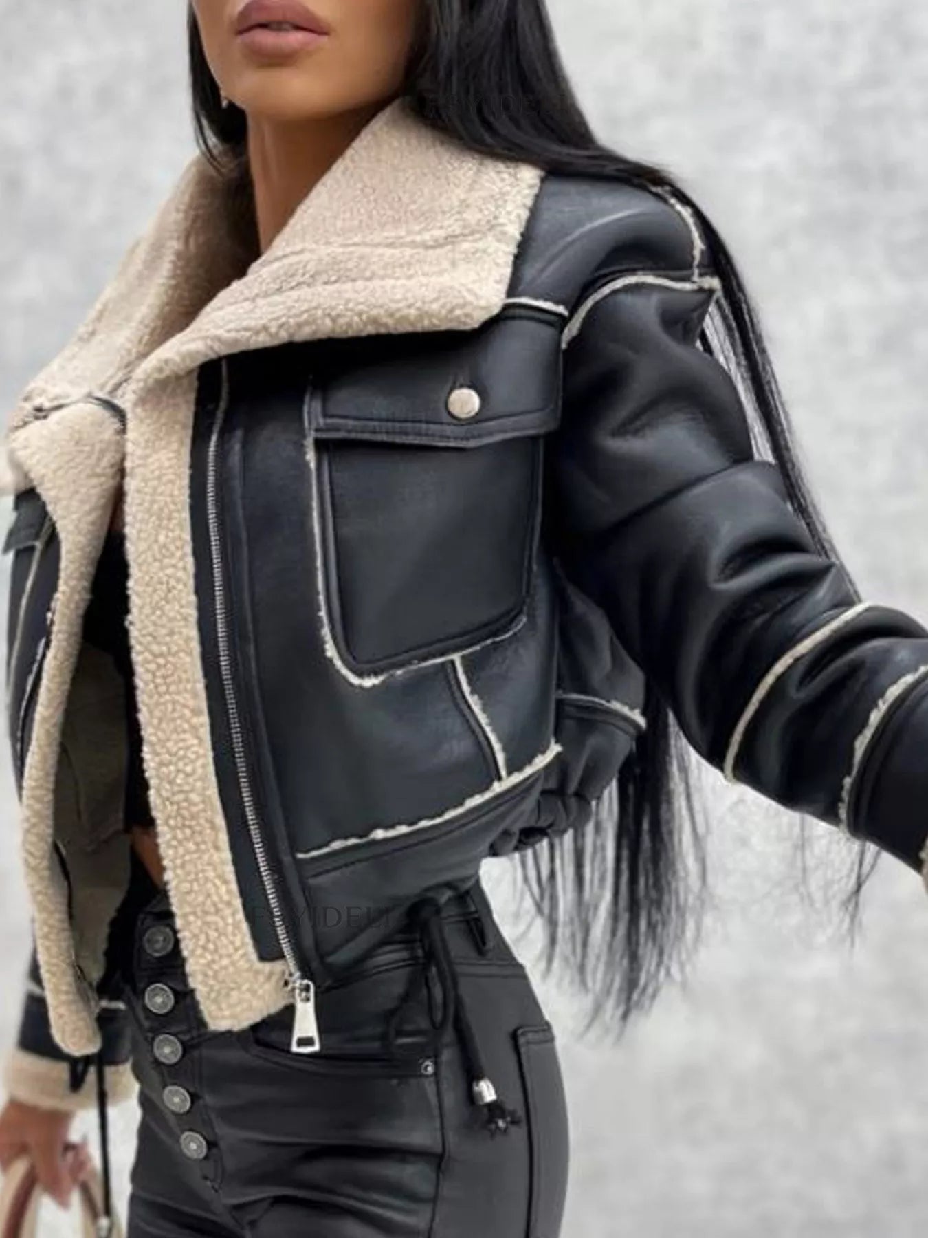 Woman wearing black leather jacket with beige shearling collar and black high-waisted leather pants