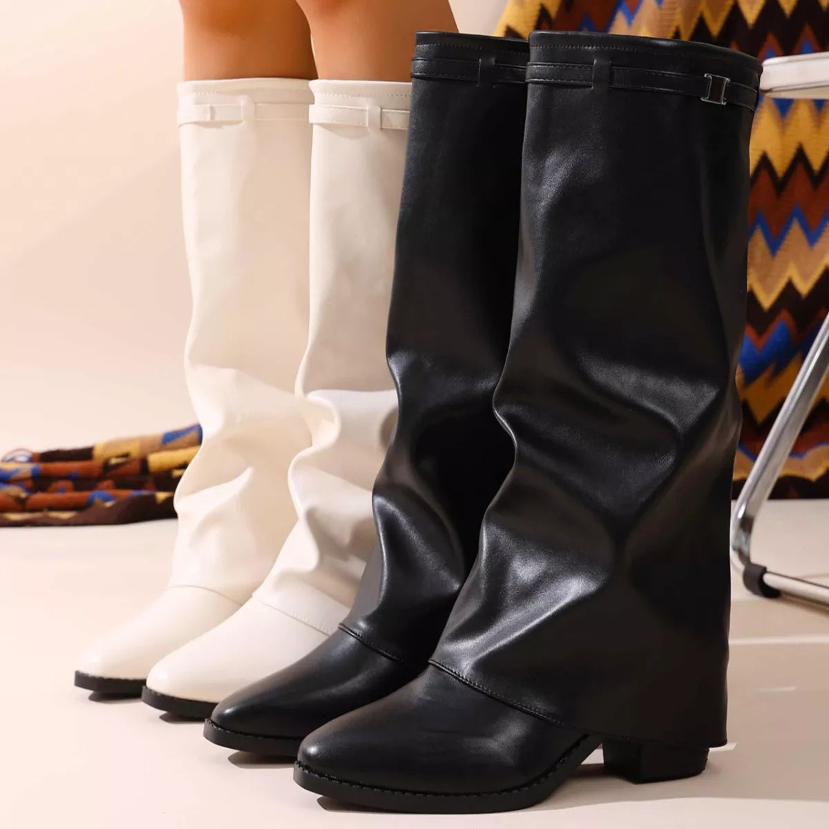 Pair of white and black slouchy knee-high boots for women.