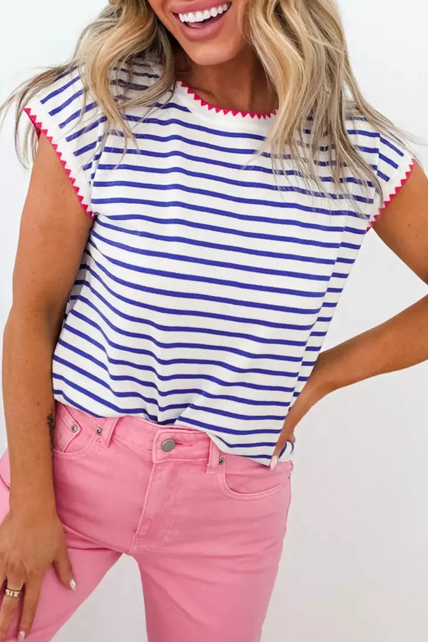 Woman wearing blue and white striped top with pink trim, paired with pink jeans for a stylish casual look