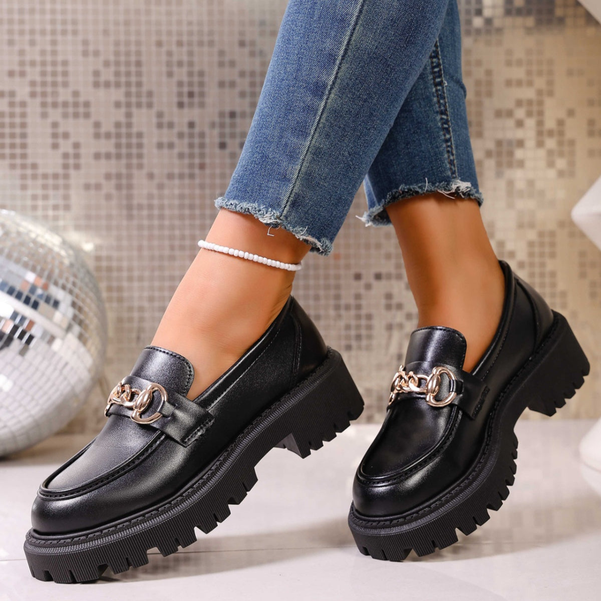 Angled view of black slip-on chain detail mid heel loafers