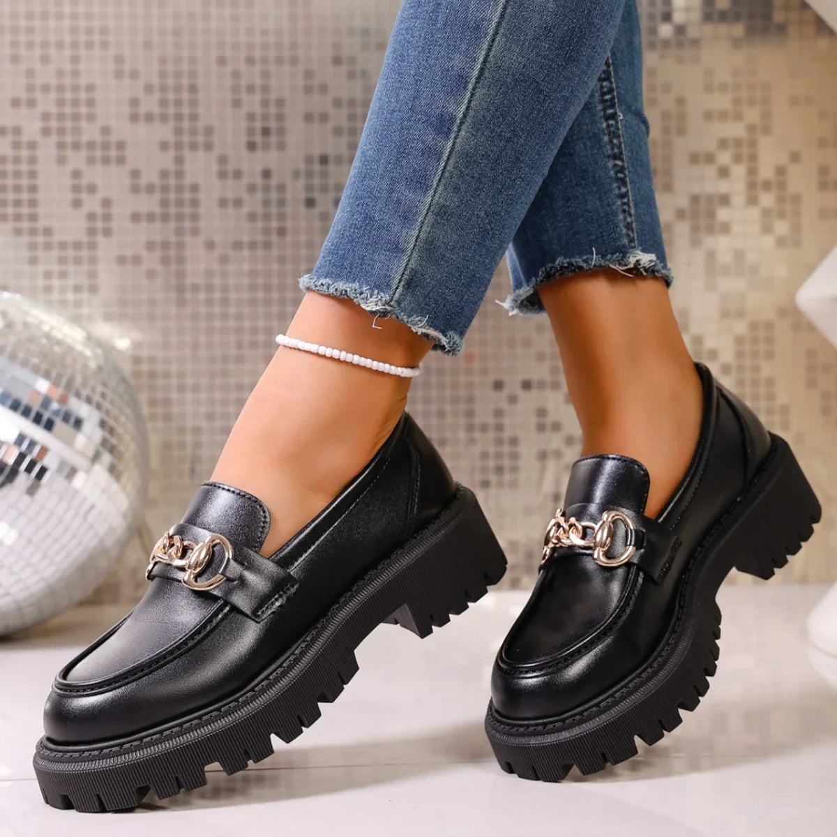 Angled view of black slip-on chain detail mid heel loafers