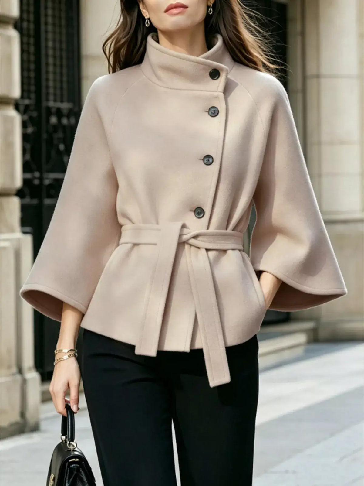Woman wearing a beige Evie's Dreamland button-down cape coat with a belted waist and high collar.