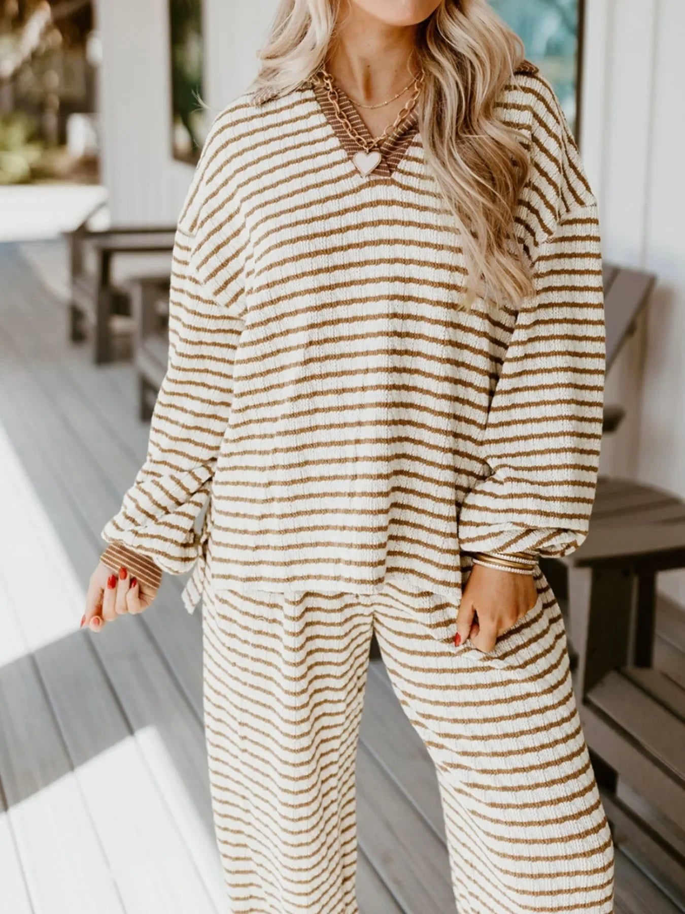 Woman wearing cozy cream and brown striped loungewear set with v-neck, standing on porch