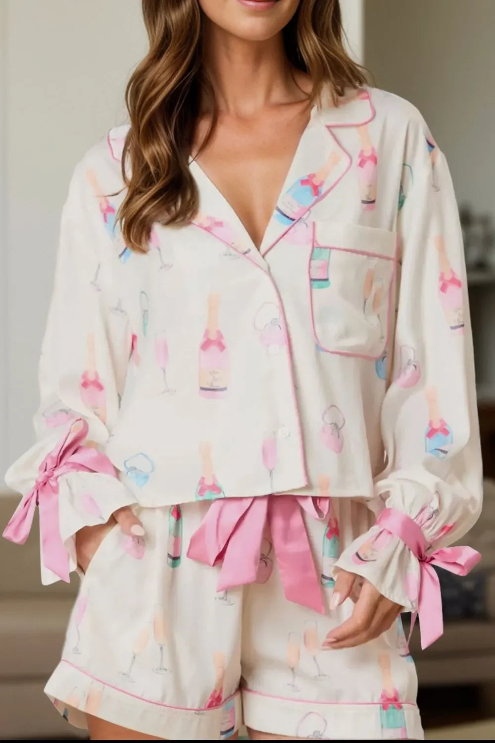 Woman wearing champagne print pajama set with pink bows on sleeves and waistband