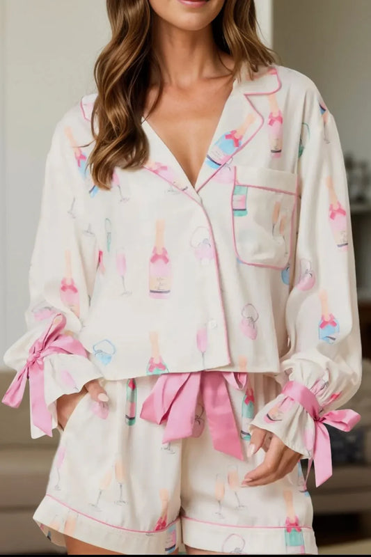 Woman wearing champagne print pajama set with pink bows on sleeves and waistband