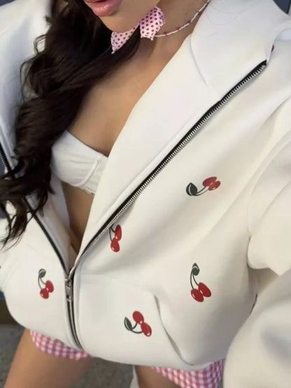 Woman wearing white zip-up jacket with red cherry prints and white bandeau top