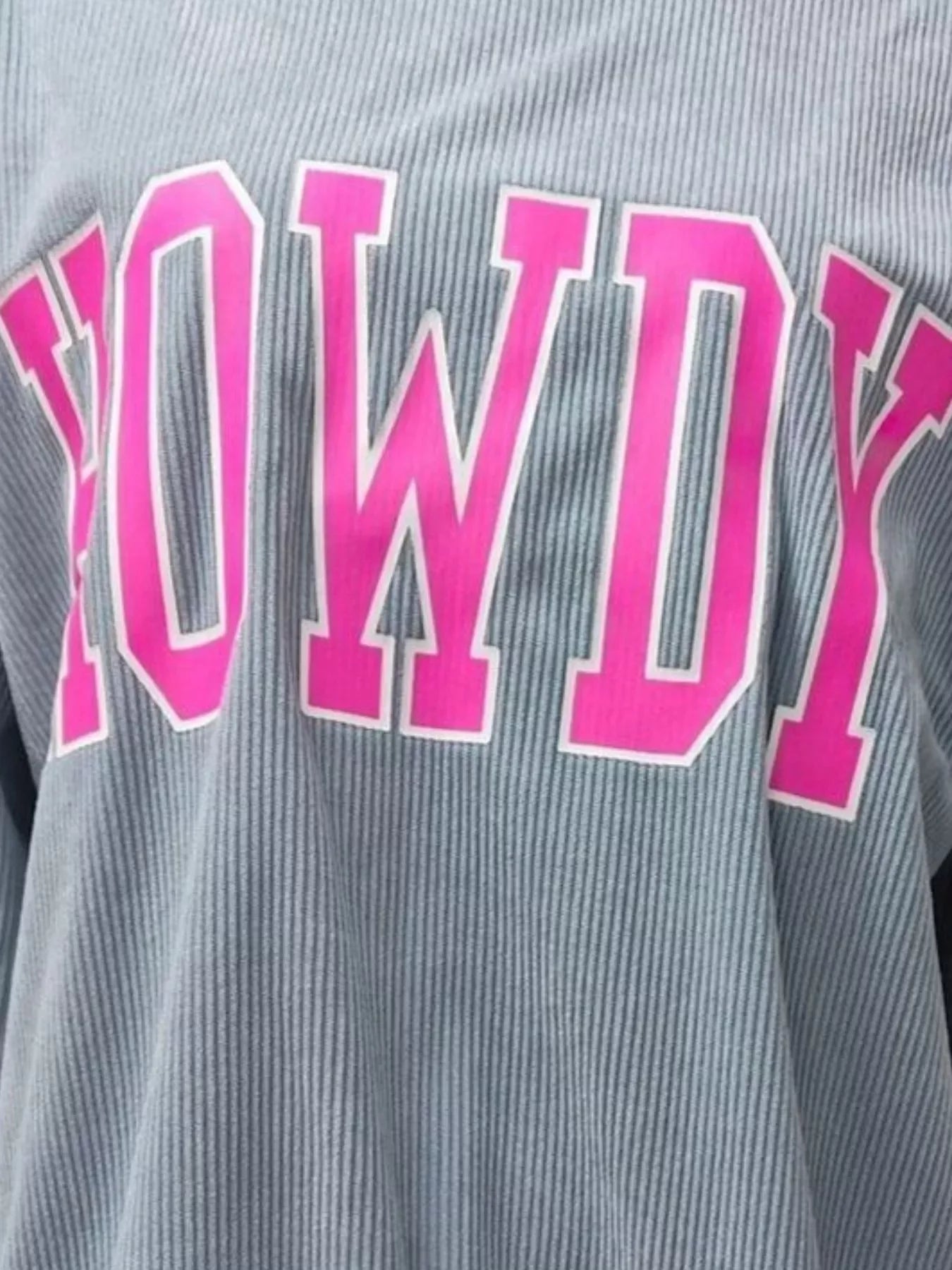 Close-up of grey ribbed fabric with bright pink letters spelling 'HOWDY'
