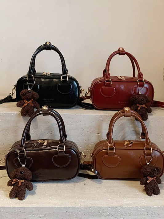 Four vintage mini PU leather crossbody bags in black, red, dark brown, and tan with bear charms