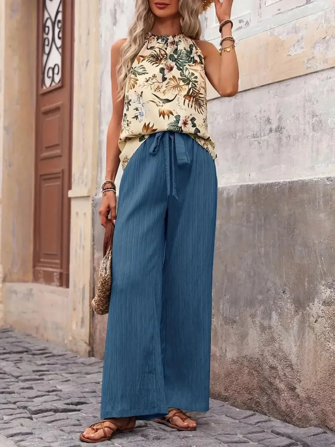 Woman in a sleeveless floral top and wide-leg blue pants, casual summer street style