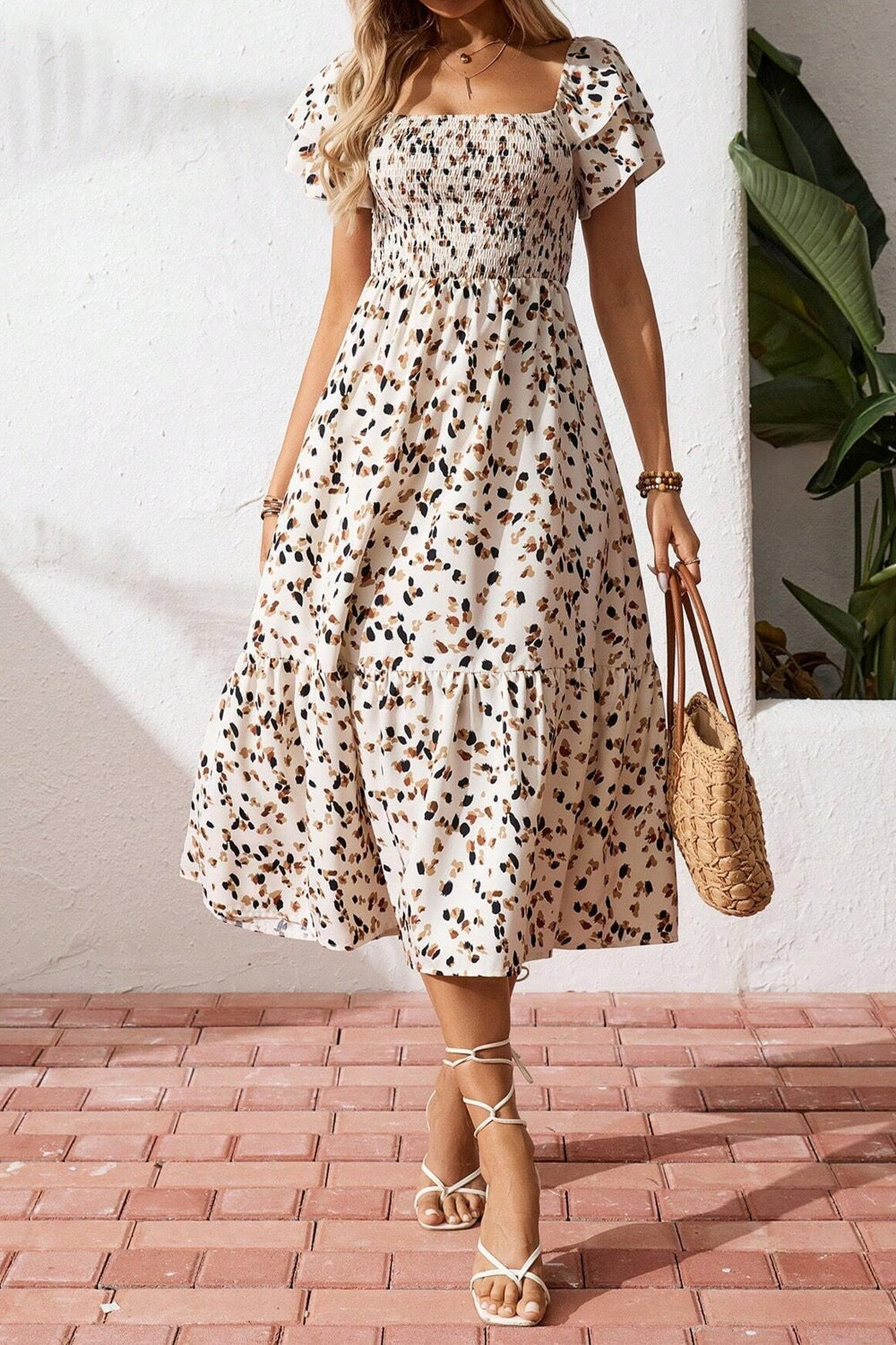 Floral print midi dress with puff sleeves, tiered skirt, and square neckline, paired with woven bag and sandals