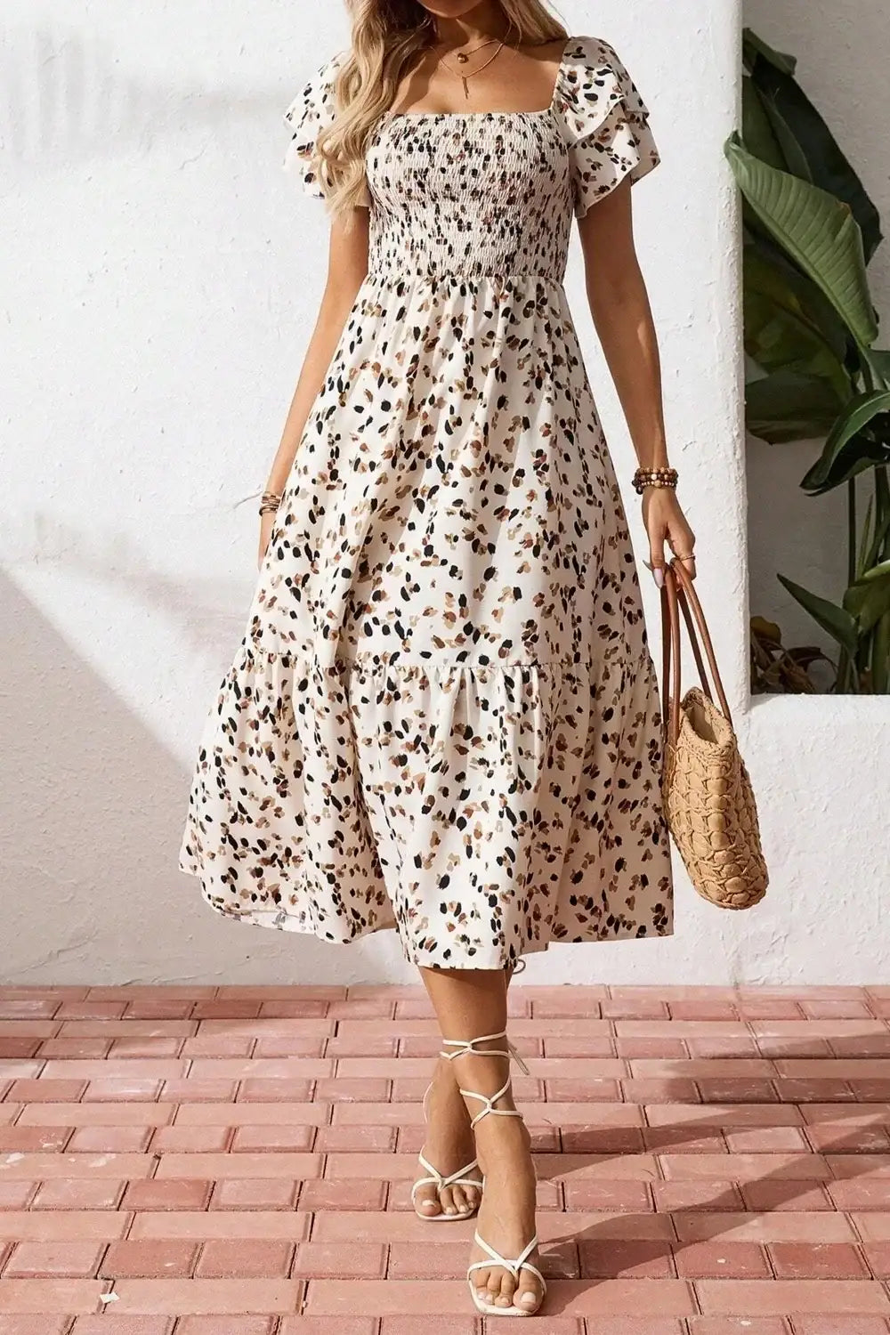 Floral print midi dress with puff sleeves, tiered skirt, and square neckline, paired with woven bag and sandals