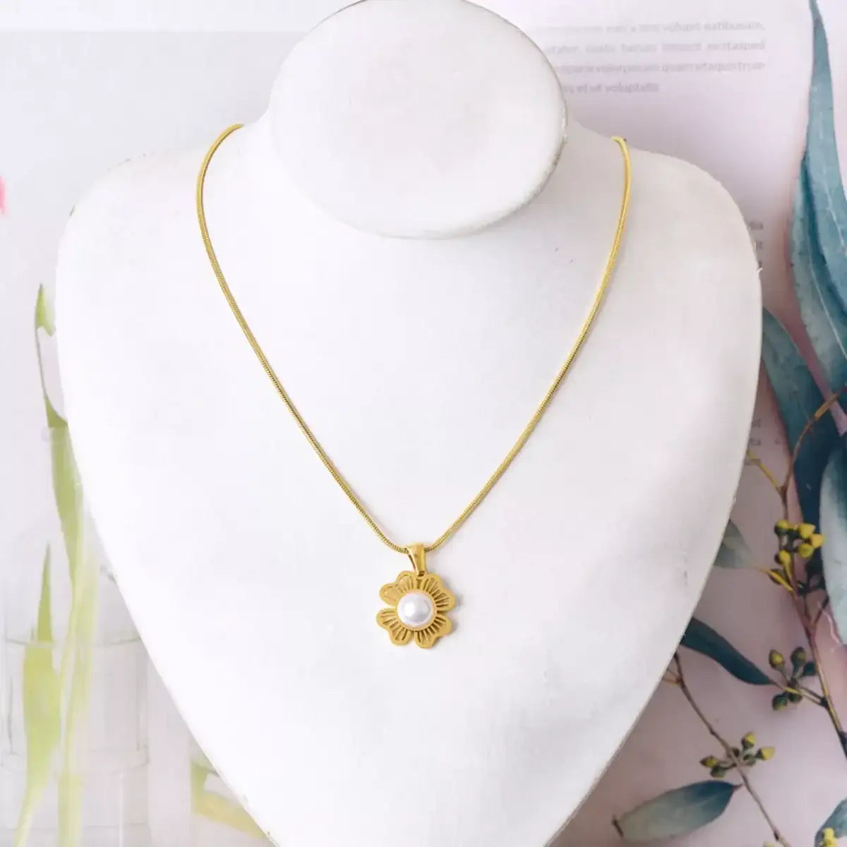 18K gold-plated flower necklace with a center pearl pendant on a white jewelry display.