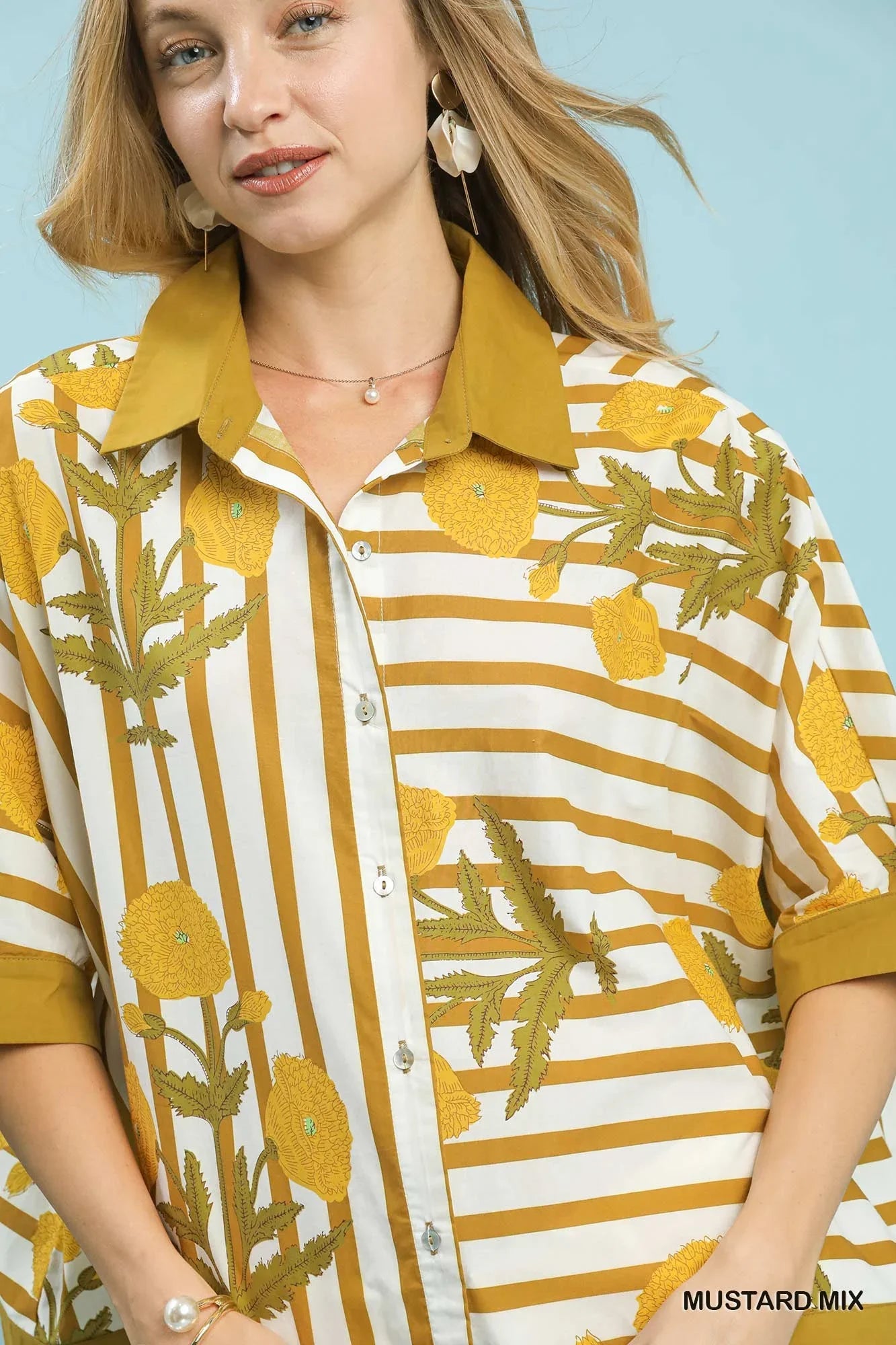 Woman wearing a mustard yellow floral striped button-up blouse with a solid collar
