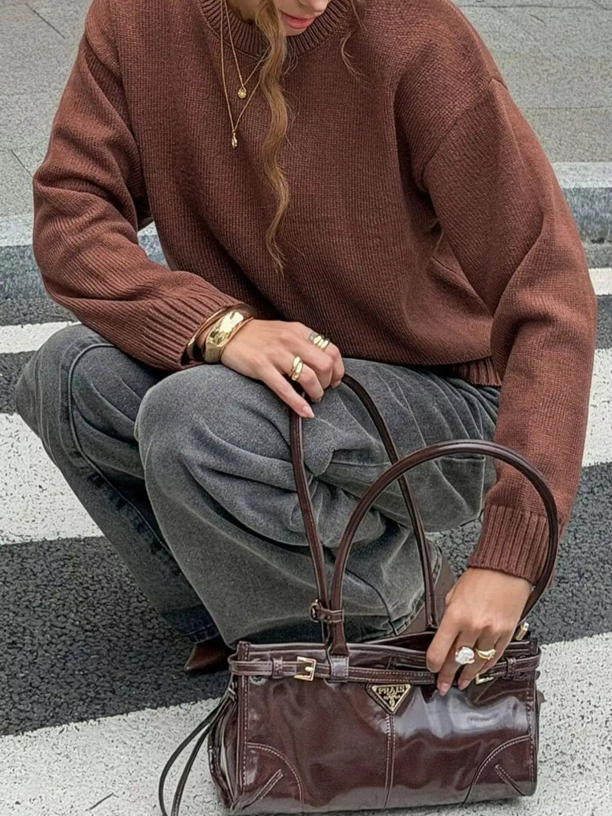 Woman wearing a brown crew neck ribbed hem sweater by Evie's Dreamland with grey pants and a handbag.