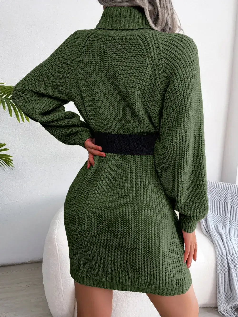 Back view of a women's olive green knit turtleneck sweater dress with a black waist belt by Evie's Dreamland.