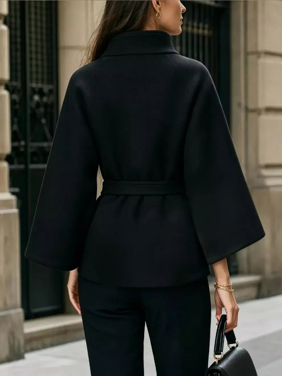 Back view of a black belted cape coat by Evie's Dreamland with wide sleeves and a high collar.
