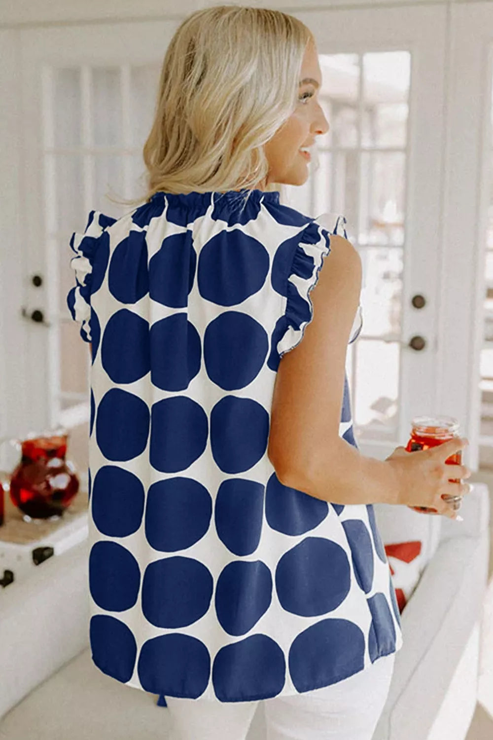 Woman in navy blue polka dot sleeveless top with ruffle details, stylish everyday fashion