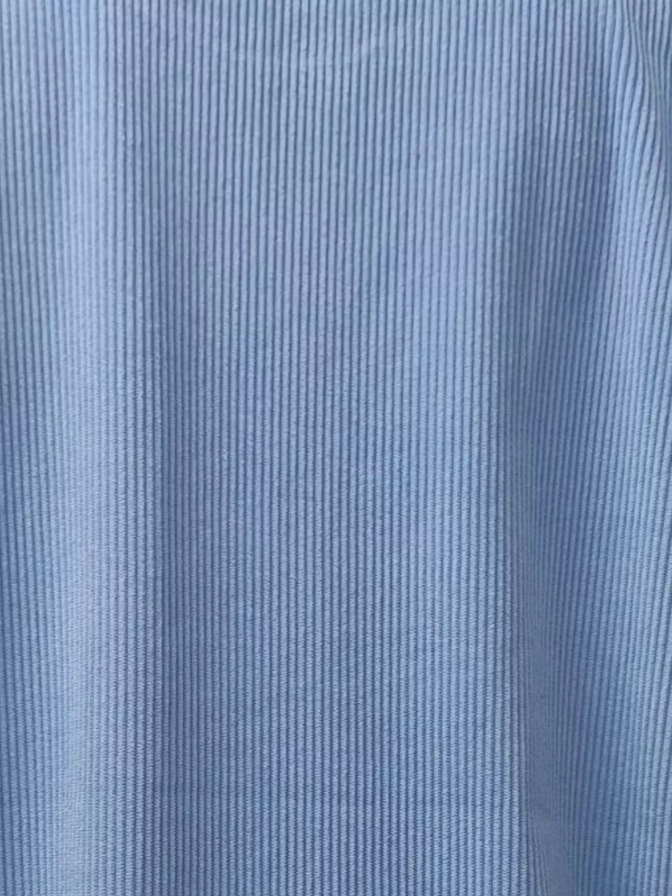 Close-up of light blue ribbed fabric texture with vertical lines and soft folds