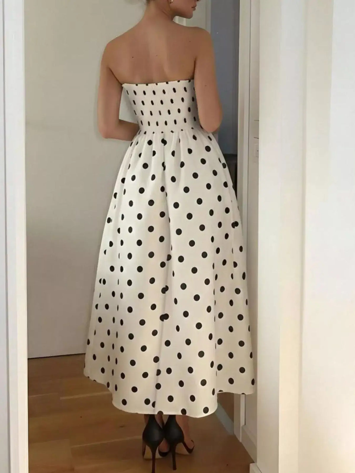 Back view of a white strapless midi dress with black polka dots and a flared skirt by Evie's Dreamland.