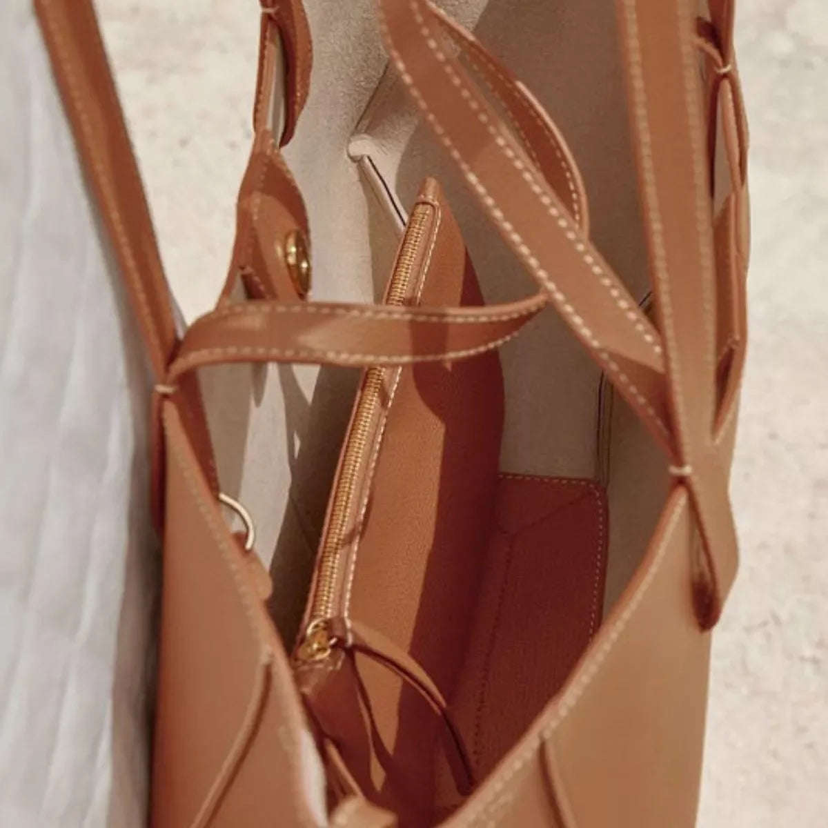 Top view inside tan leather tote bag showing beige interior and zippered pouch with gold zipper
