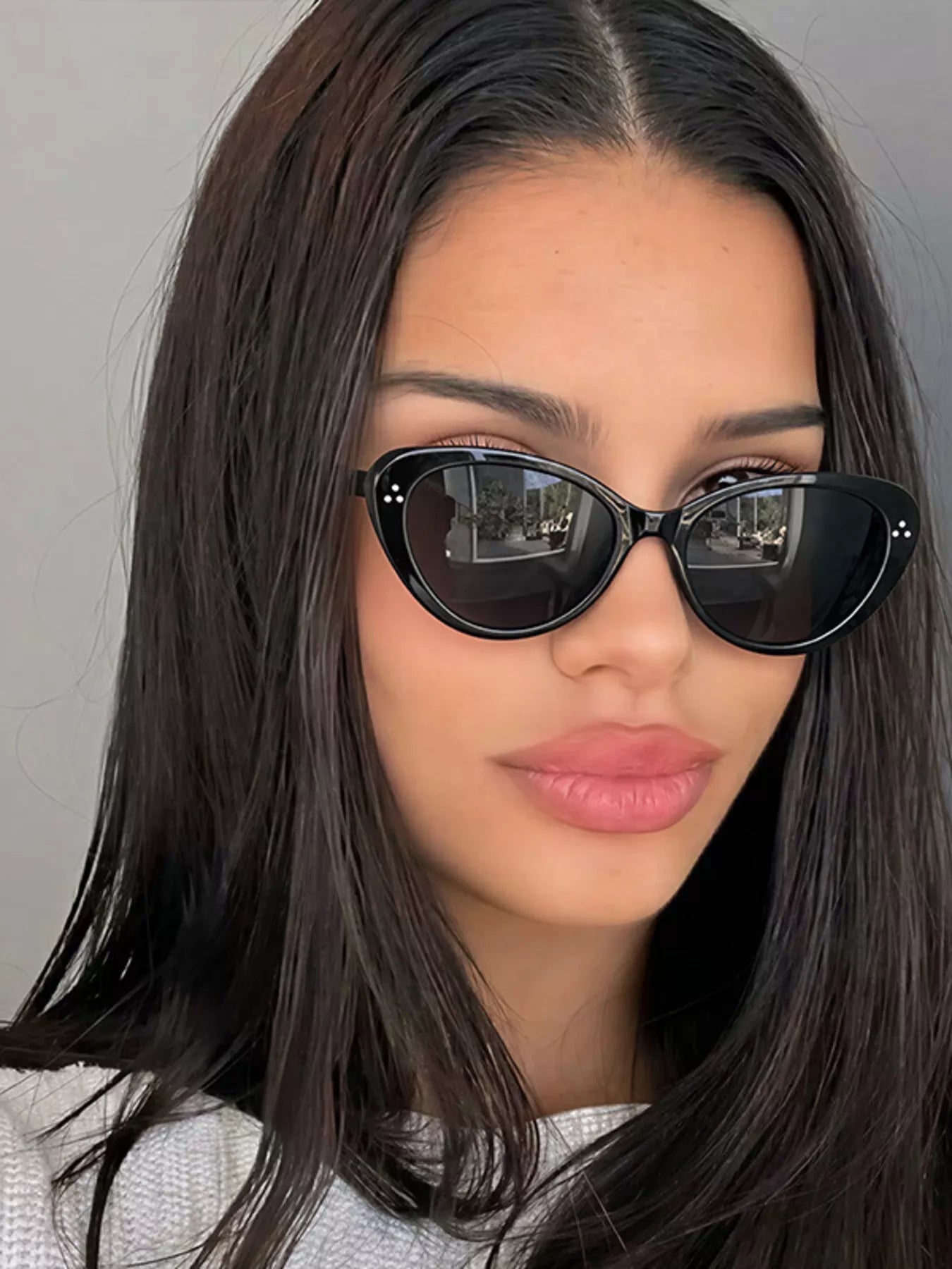 Close-up of a woman wearing black cat-eye sunglasses with small silver accents.