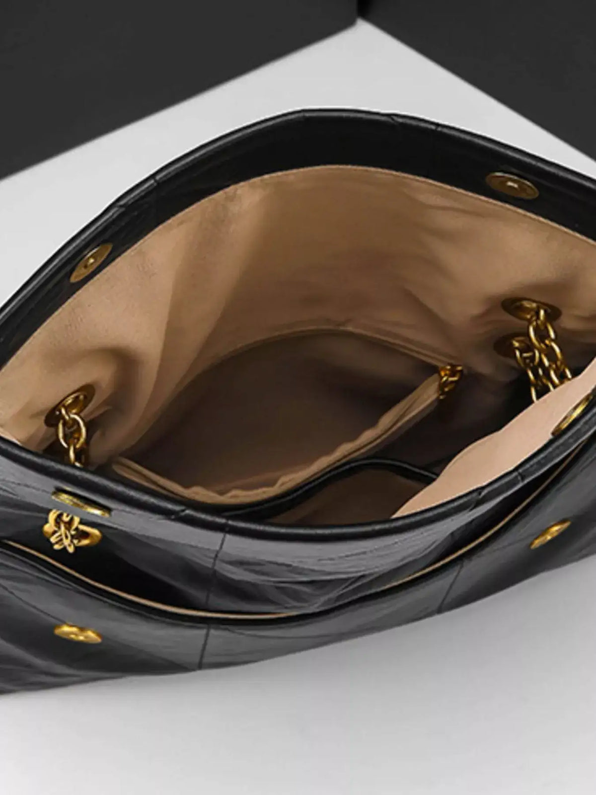 Interior view of a black geometric quilted PU leather shoulder bag by Evie's Dreamland with gold chain straps.