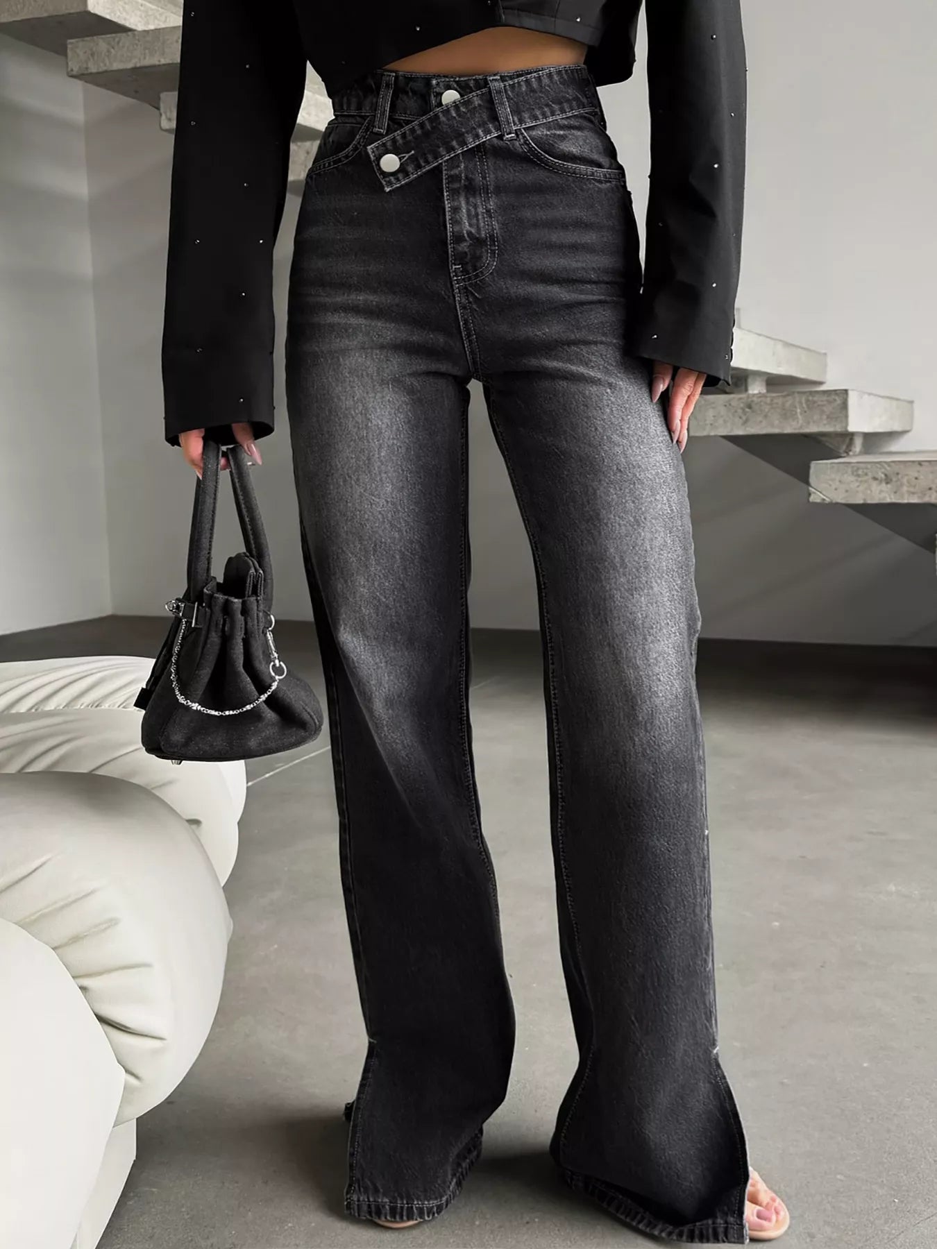 High-waisted black wide-leg jeans with crossover waistband, styled with a small handbag