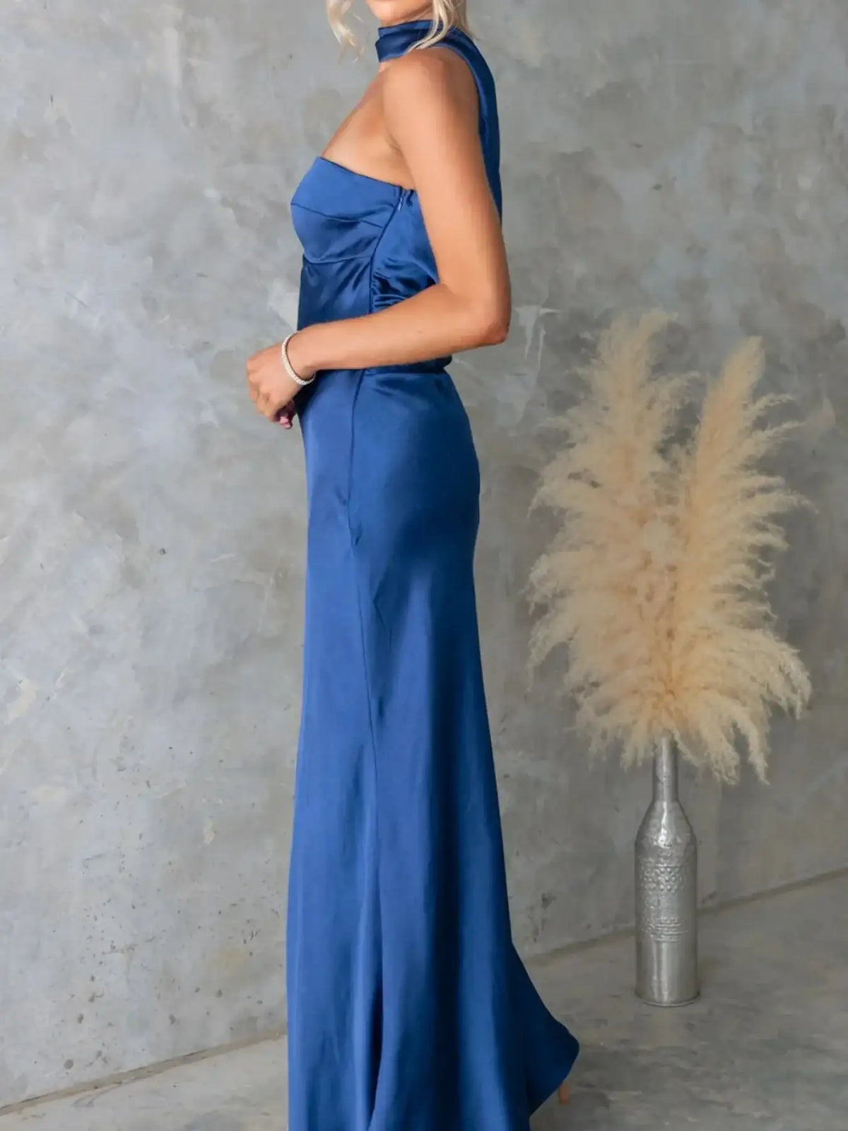 Woman wearing a royal blue satin tube maxi dress by Evie's Dreamland with a halter-style neckline.
