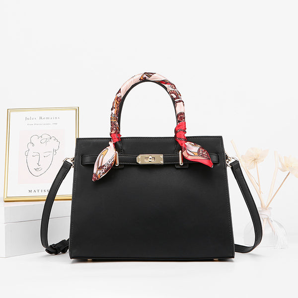 Black structured handbag with gold clasp, colorful scarf-wrapped handles, and detachable strap