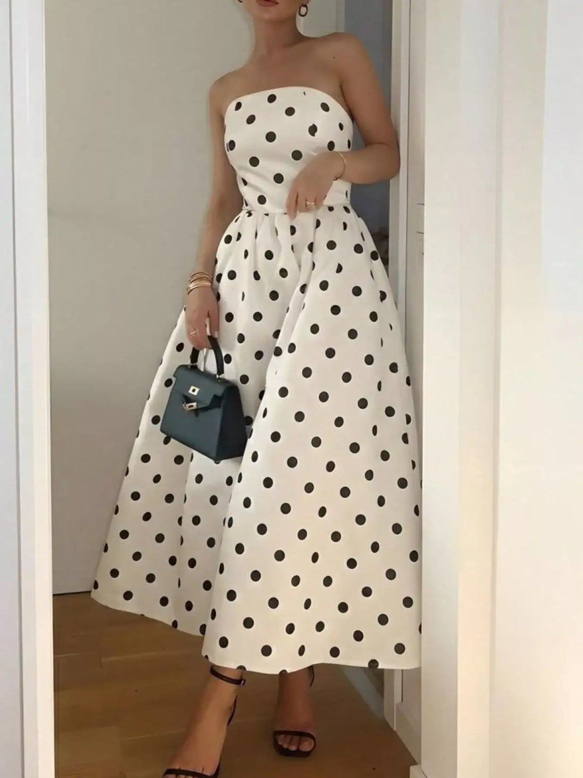 Woman wearing an Evie's Dreamland strapless white midi dress with black polka dots and a full skirt.