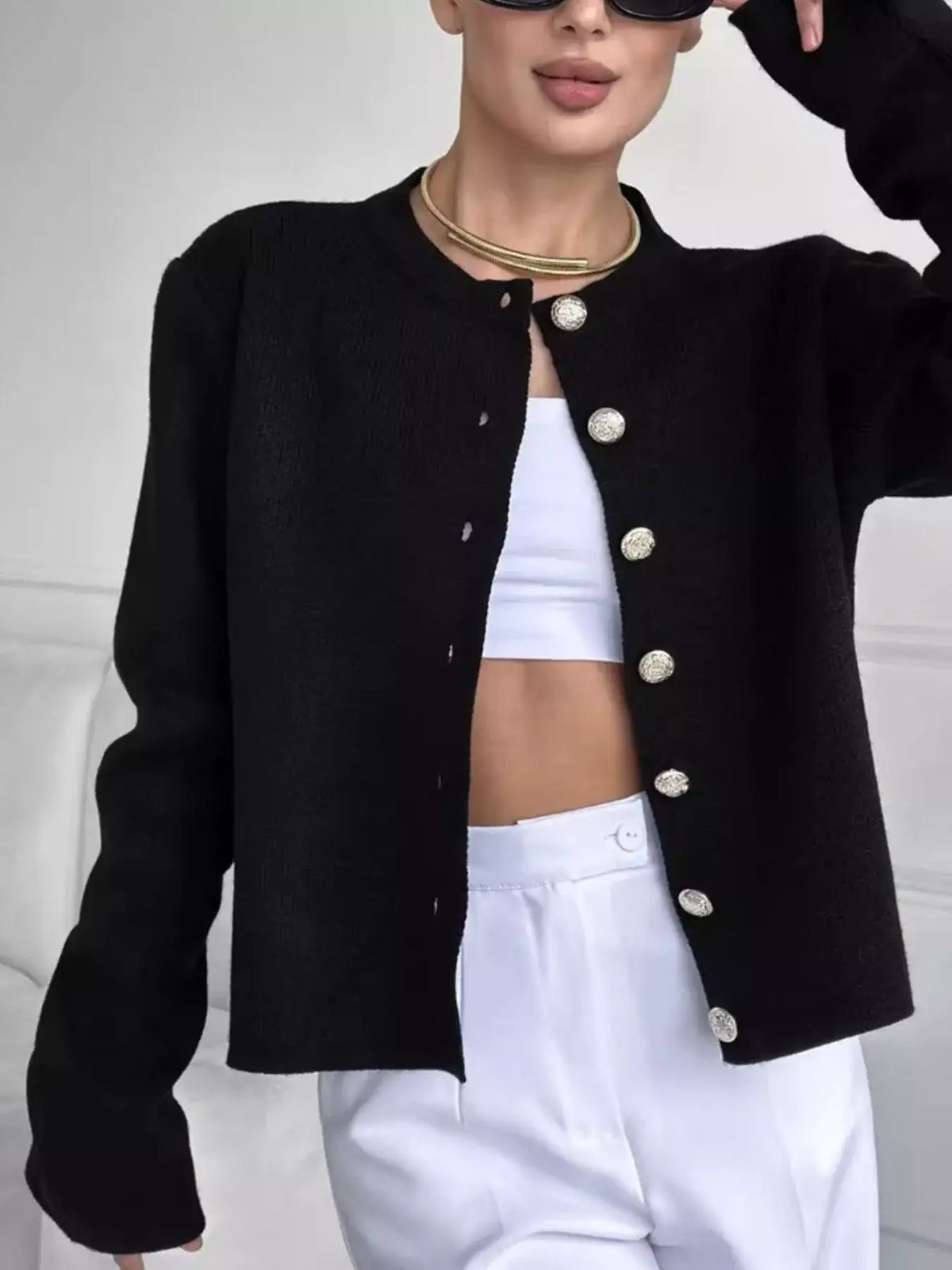 Black crew neck button down cardigan from Evie's Dreamland with gold buttons, styled with white pants.