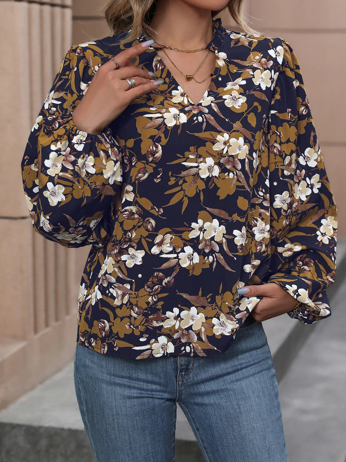 Woman wearing navy blue floral long-sleeve blouse with brown and white flowers, paired with blue jeans