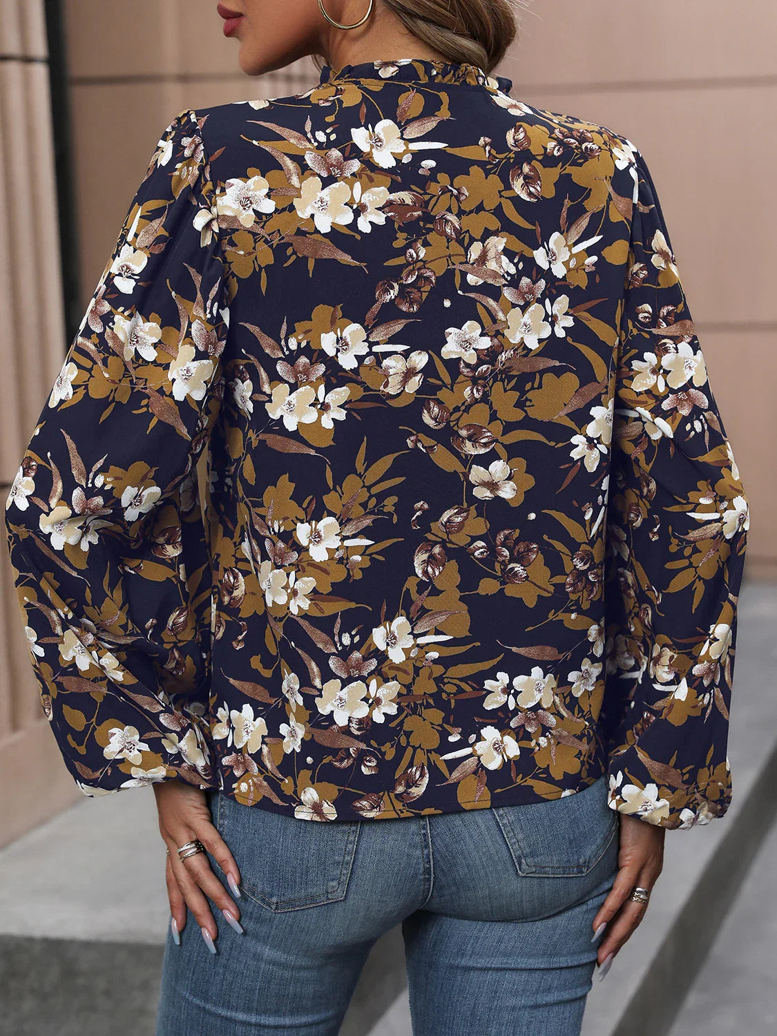 Woman wearing navy floral long sleeve blouse and blue denim jeans with gold hoop earrings