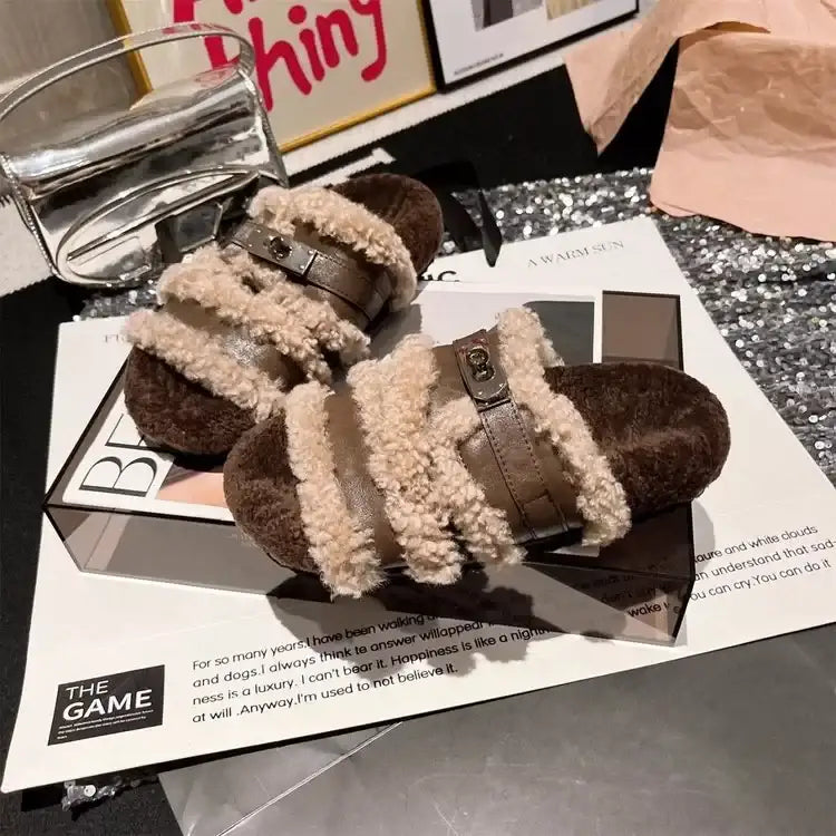 Evie's Dreamland brown plush faux fur slippers with adjustable buckle straps on a magazine.