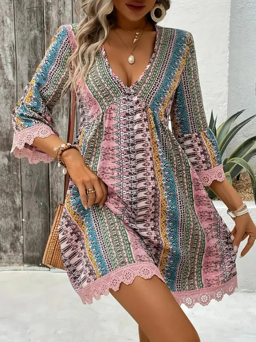 Woman wearing a colorful boho mini dress with lace trim and v-neck outdoors