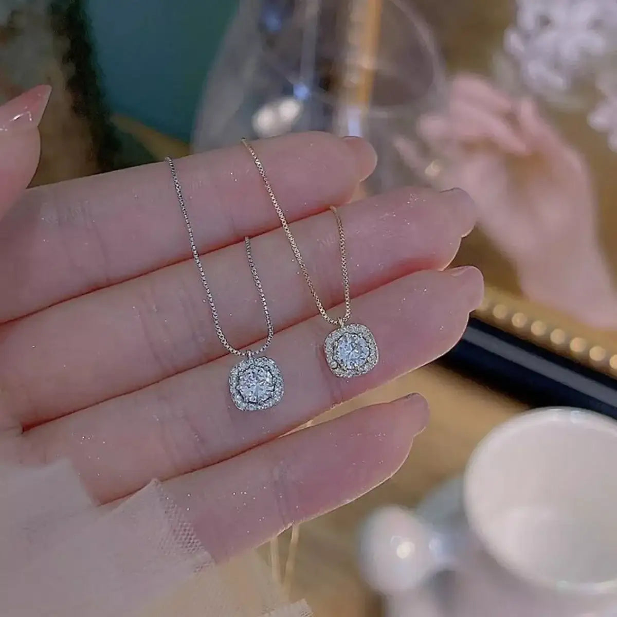 Two Evie's Dreamland 925 sterling silver zircon pendant necklaces held in a person's hand.