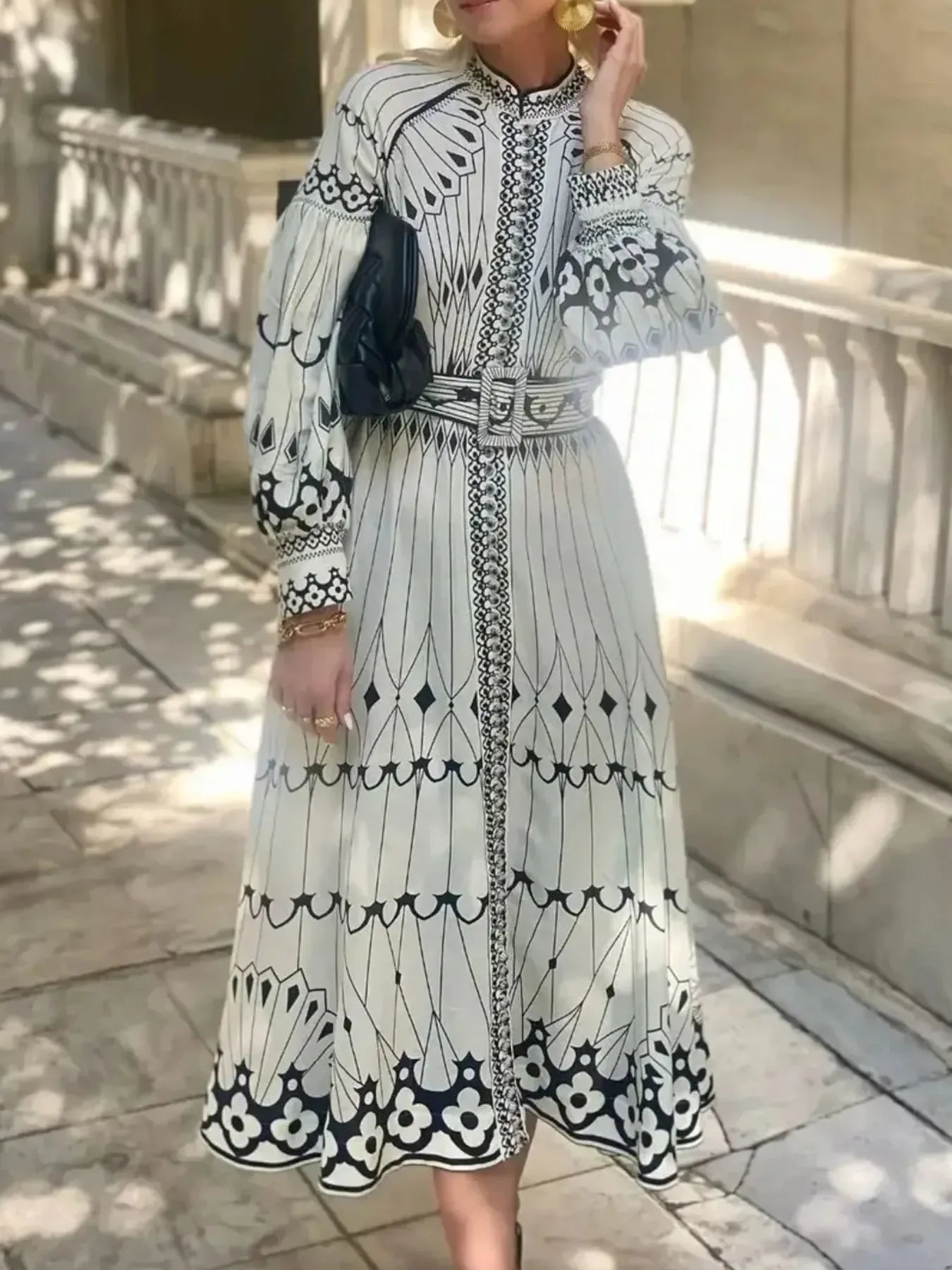 Woman wearing white midi dress with black geometric floral patterns and puffed sleeves